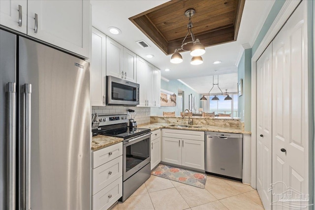 kitchen featuring a raised ceiling, white cabinetry, sink, stainless steel appliances, and crown molding