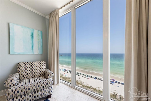 living area featuring a view of the beach, light tile patterned floors, crown molding, and a water view