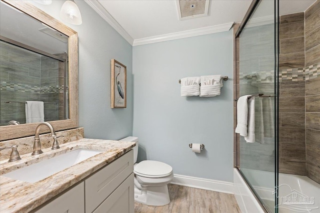 full bathroom with crown molding, hardwood / wood-style floors, bath / shower combo with glass door, vanity, and toilet