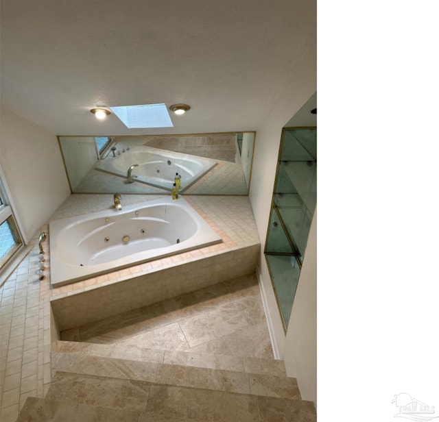 bathroom with tiled bath and a skylight