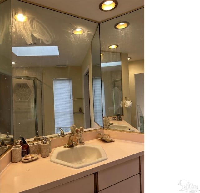 bathroom with vanity, a skylight, and a shower with door