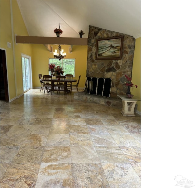 dining room with a stone fireplace, a chandelier, and vaulted ceiling