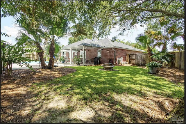 1707 Cedrus Ln, Pensacola, FL 32514 - back of property featuring a fenced backyard, a patio, a fire pit, and brick siding