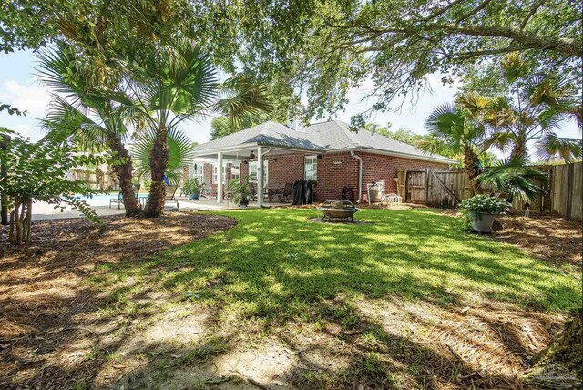 1707 Cedrus Ln, Pensacola, FL 32514 - back of house with a fenced backyard, a patio, a fire pit, and brick siding