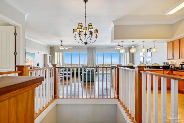 corridor featuring an inviting chandelier, sink, a wealth of natural light, and ornamental molding