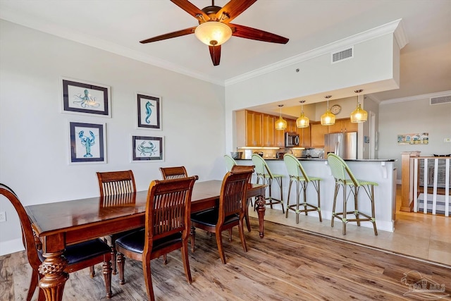 dining space featuring ceiling fan, ornamental molding, and light hardwood / wood-style floors