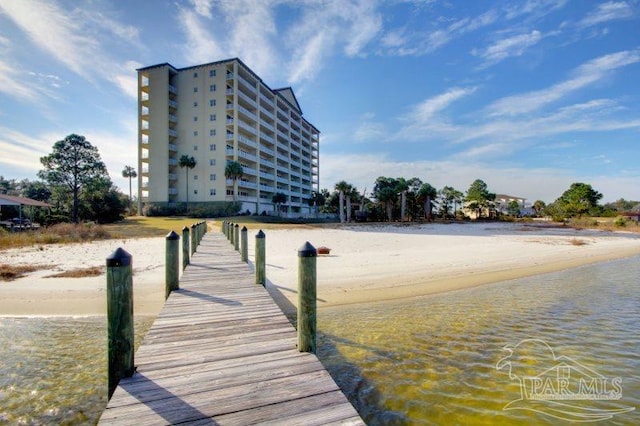 view of dock with a water view and a beach view