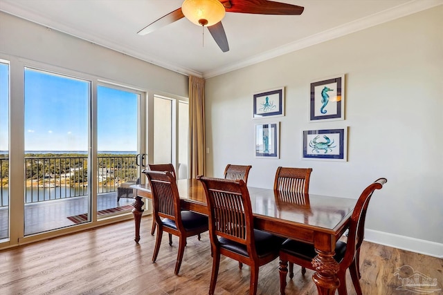 dining room with wood-type flooring, a water view, ceiling fan, and crown molding