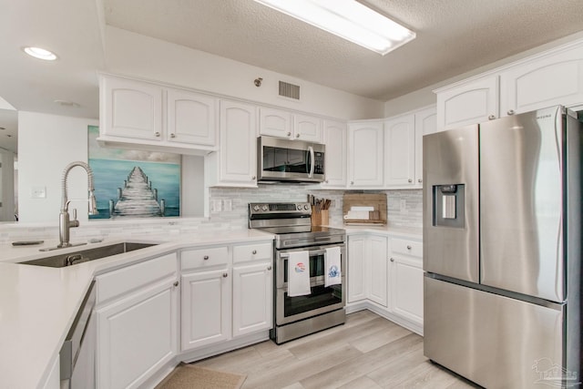 kitchen featuring white cabinets, visible vents, stainless steel appliances, and a sink