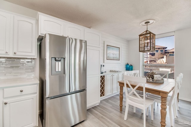 kitchen with light wood-style flooring, white cabinets, backsplash, and stainless steel fridge with ice dispenser