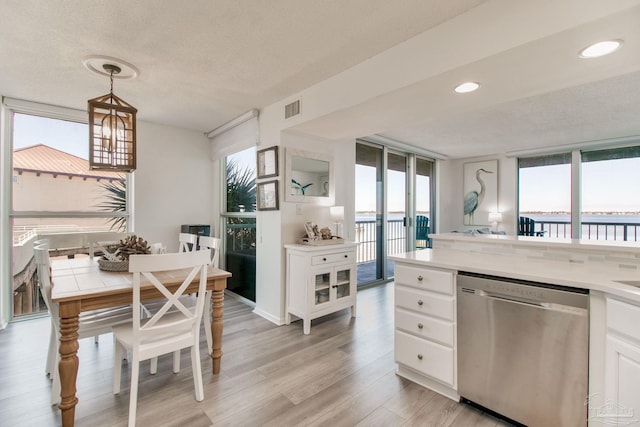 kitchen with visible vents, white cabinetry, light countertops, light wood-type flooring, and dishwasher