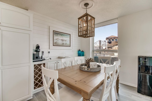 dining area featuring a textured ceiling, an inviting chandelier, and light wood-style floors