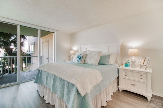 bedroom with a textured ceiling, access to outside, light wood-style flooring, and floor to ceiling windows