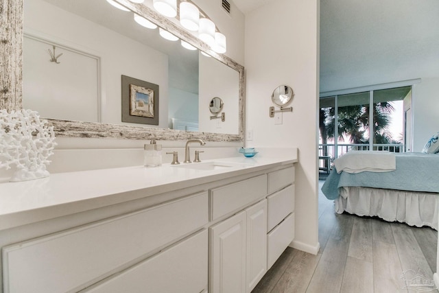 ensuite bathroom with visible vents, connected bathroom, vanity, and wood finished floors