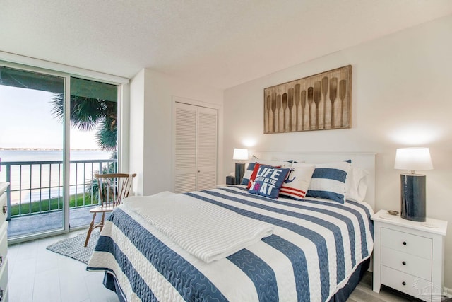 bedroom featuring expansive windows, a closet, a textured ceiling, and access to exterior