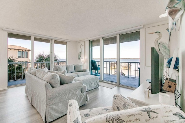 living room with floor to ceiling windows, a textured ceiling, and light wood finished floors