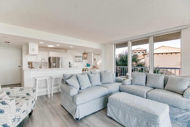 living room with light wood-style floors, a textured ceiling, and recessed lighting