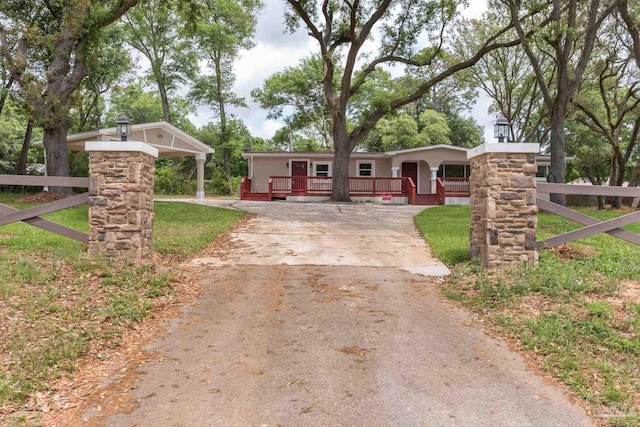 single story home with a porch, fence, and concrete driveway