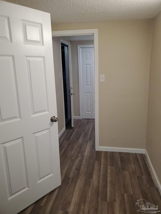 corridor featuring a textured ceiling and dark hardwood / wood-style floors