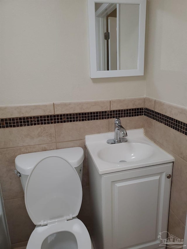 bathroom featuring vanity, tile walls, and toilet