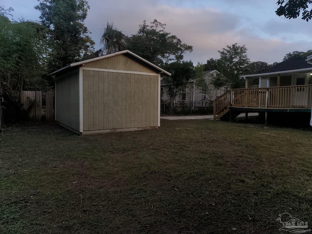 yard at dusk featuring a storage shed and a wooden deck