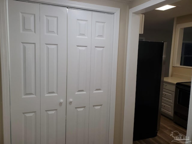 interior details with black electric range, hardwood / wood-style floors, and fridge