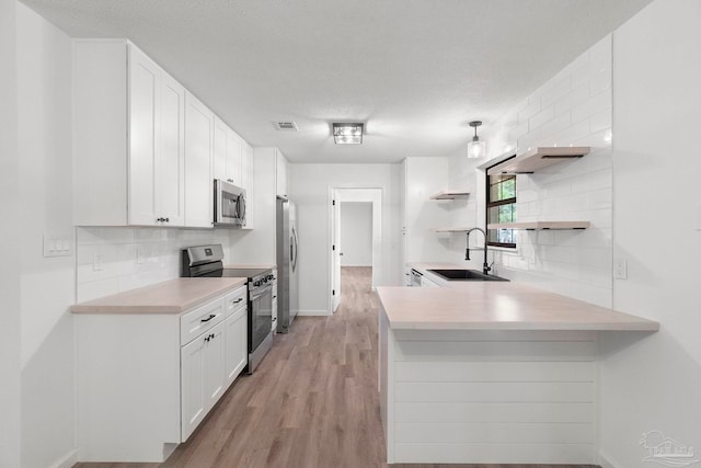 5547 Kauffman Rd, Milton, FL 32583 - kitchen featuring stainless steel appliances, a sink, backsplash, white cabinetry, and a textured ceiling
