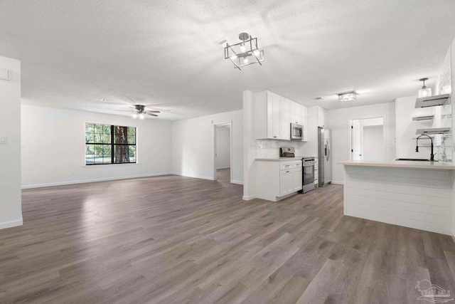 5547 Kauffman Rd, Milton, FL 32583 - unfurnished living room with a sink, a textured ceiling, wood finished floors, baseboards, and ceiling fan