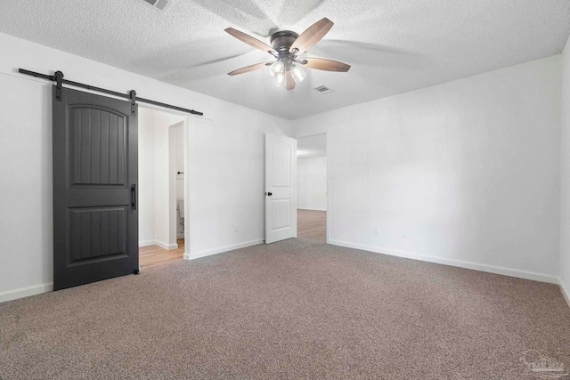 5547 Kauffman Rd, Milton, FL 32583 - unfurnished bedroom featuring a barn door, carpet floors, a textured ceiling, a ceiling fan, and baseboards