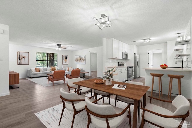 5547 Kauffman Rd, Milton, FL 32583 - dining area with light wood-style flooring, a textured ceiling, ceiling fan, and baseboards