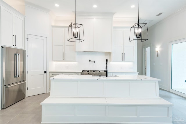 kitchen featuring high end fridge, pendant lighting, and a center island with sink