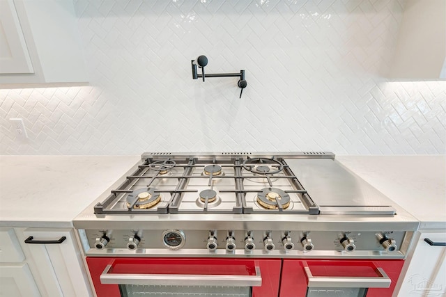 room details with white cabinetry, stainless steel gas stovetop, and decorative backsplash