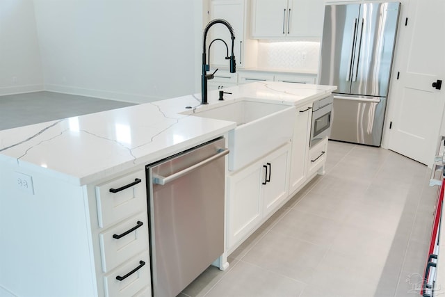 kitchen featuring white cabinetry, stainless steel appliances, light tile patterned floors, and an island with sink