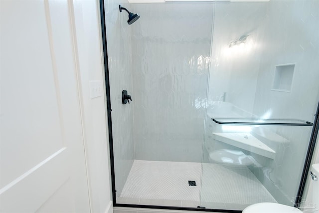 bathroom with a shower with shower door and toilet