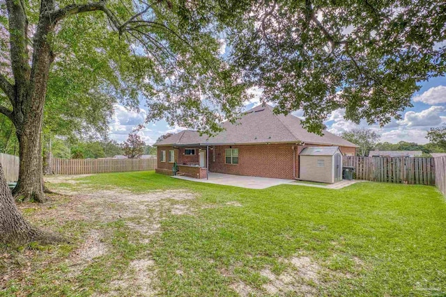 back of property with a storage shed, a lawn, and a patio area