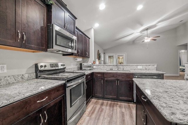 kitchen with appliances with stainless steel finishes, lofted ceiling, sink, kitchen peninsula, and light wood-type flooring