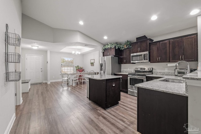 kitchen with stainless steel appliances, a center island, light stone counters, and light hardwood / wood-style flooring