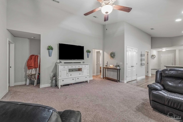 carpeted living room with a high ceiling and ceiling fan