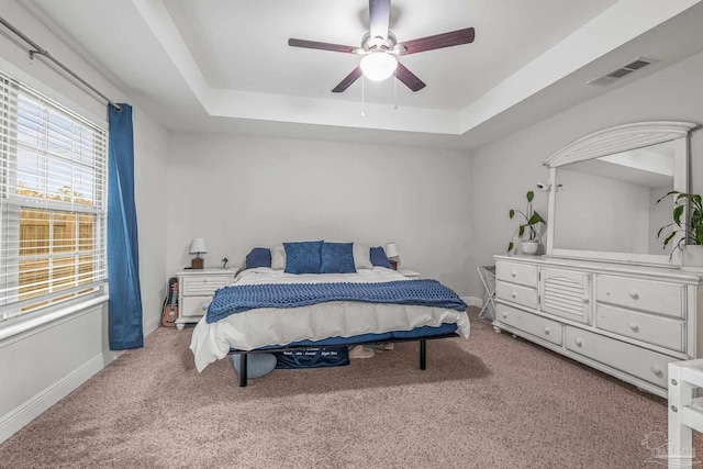 bedroom with ceiling fan, a raised ceiling, and light colored carpet