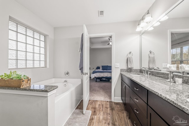 bathroom featuring wood-type flooring, a tub, vanity, and ceiling fan