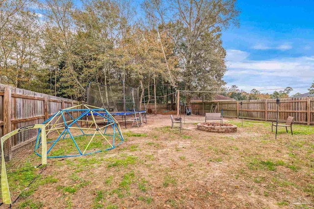 view of yard with an outdoor fire pit and a trampoline