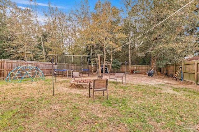 view of yard with a trampoline and an outdoor fire pit