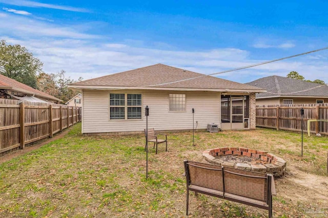 back of house featuring a lawn and an outdoor fire pit