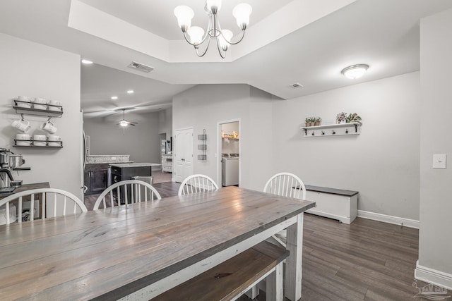 dining space with a tray ceiling, washer / clothes dryer, dark hardwood / wood-style flooring, and ceiling fan with notable chandelier