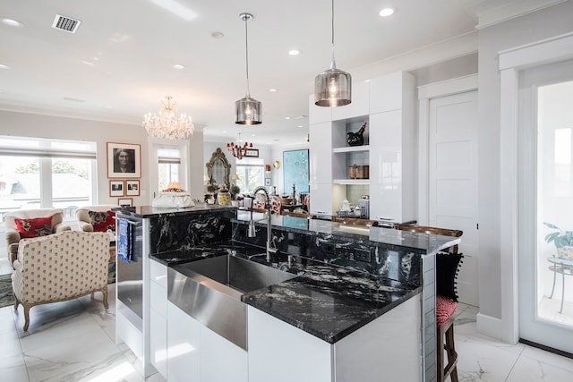 kitchen with white cabinetry, a breakfast bar, dark stone counters, a large island, and a chandelier