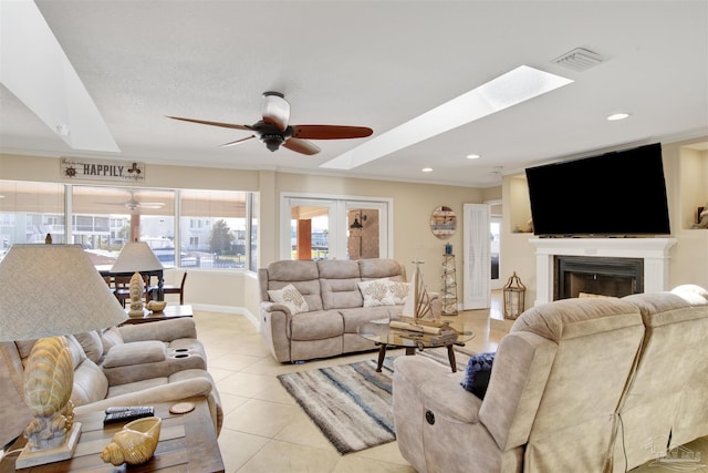 living area with light tile patterned floors, a ceiling fan, visible vents, a glass covered fireplace, and crown molding