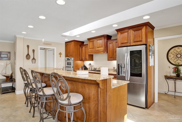 kitchen featuring ornamental molding, an island with sink, stainless steel fridge, and light stone countertops