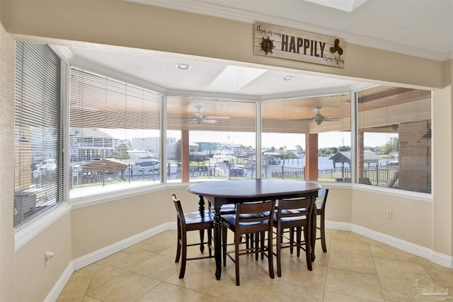 dining space with a healthy amount of sunlight, a skylight, baseboards, and a ceiling fan