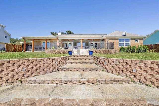 ranch-style house with covered porch, ceiling fan, a front yard, and fence