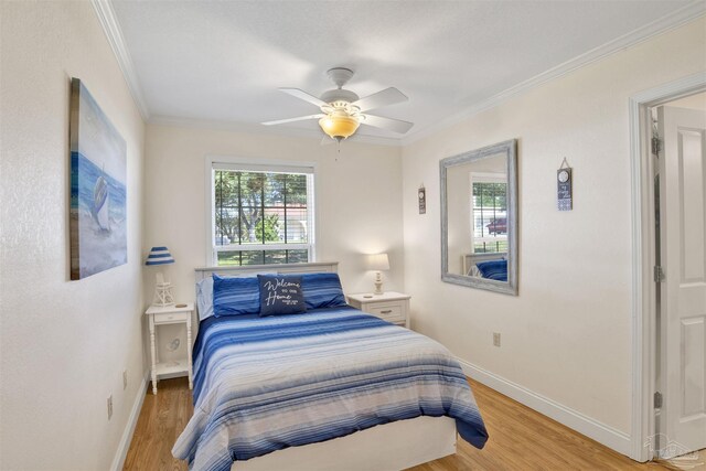 bedroom with ornamental molding, light wood-type flooring, baseboards, and a ceiling fan